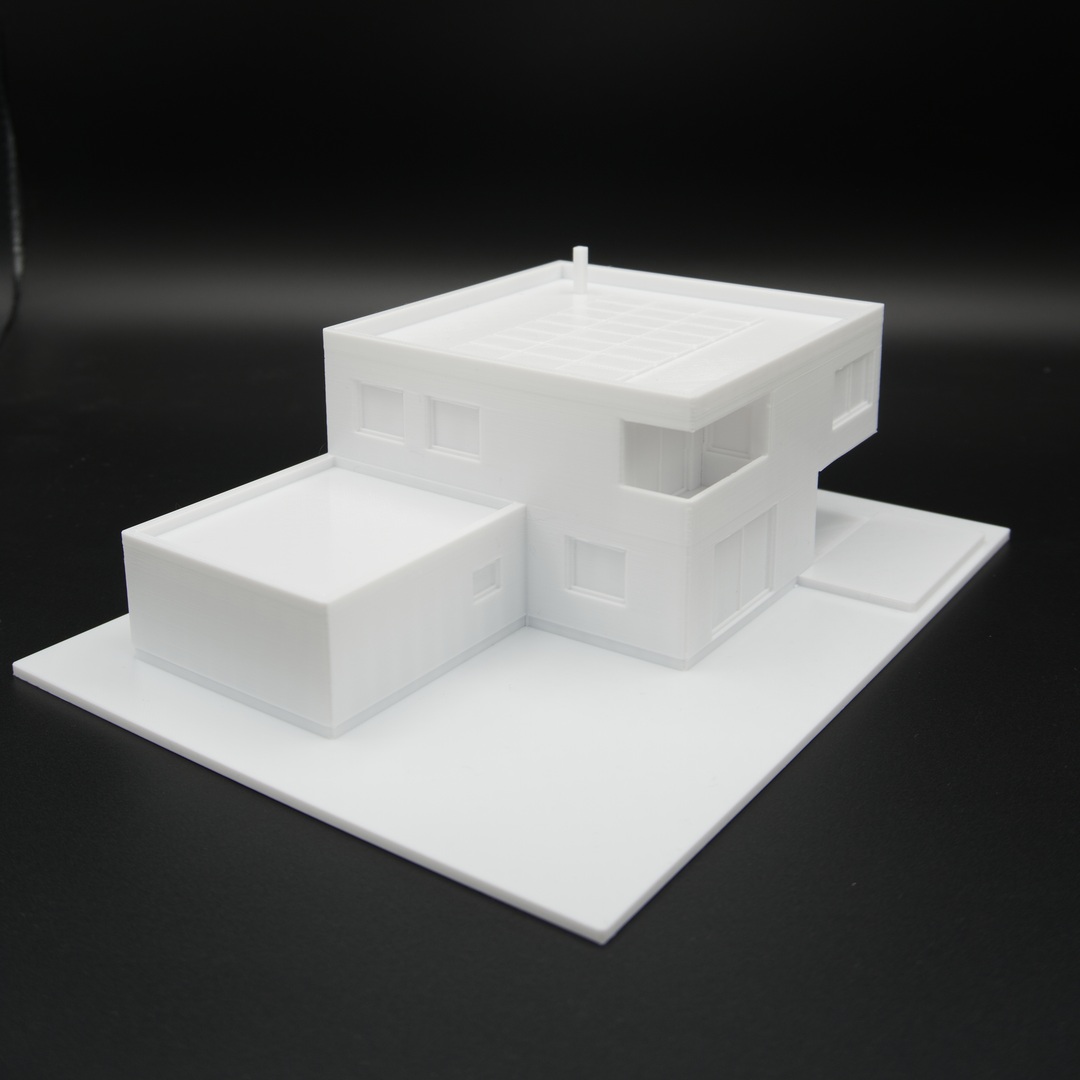 Modernes Einfamilienhaus als weißes 3D-Druck-Modell im Maßstab 1:100 mit Garage und Grundstücksplatte