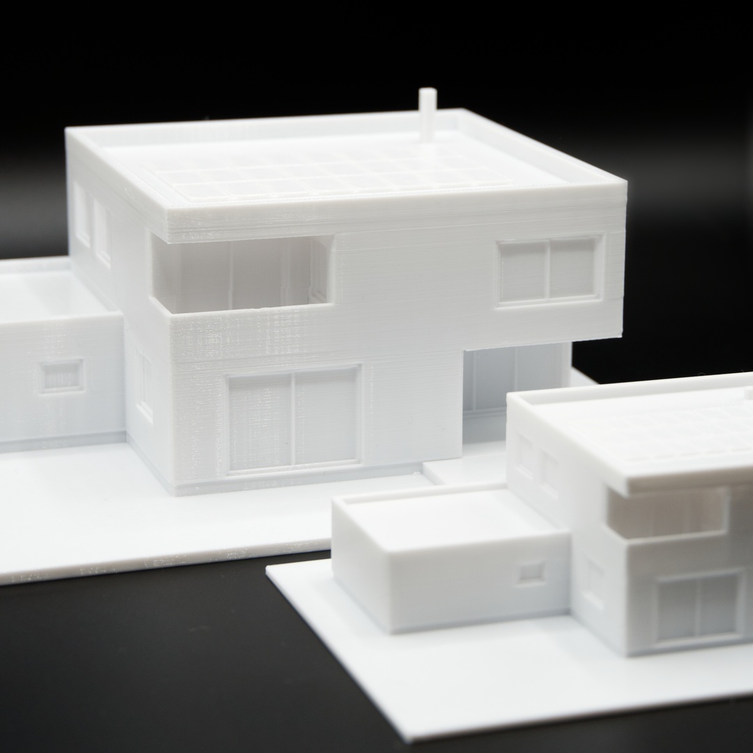 Zwei weiße Einfamilienhaus-Modelle im Maßstab 1:100 mit Balkonnische und Flachdach